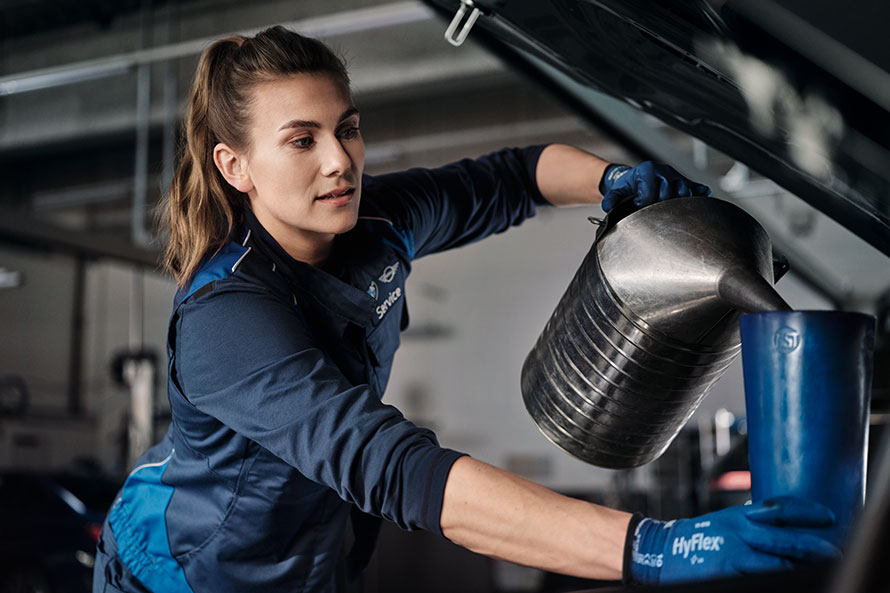 BMW serwis - kobieta wymienia olej w samochodzie.