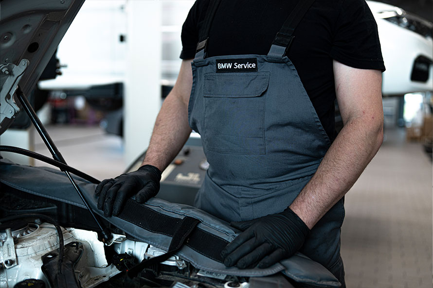 BMW serwis - mężczyzna otwiera maskę samochodu.